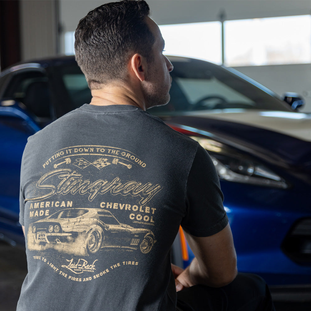 Man sitting in front of a Corvette wearing the 1969 Stingray Putting It Down T-shirt