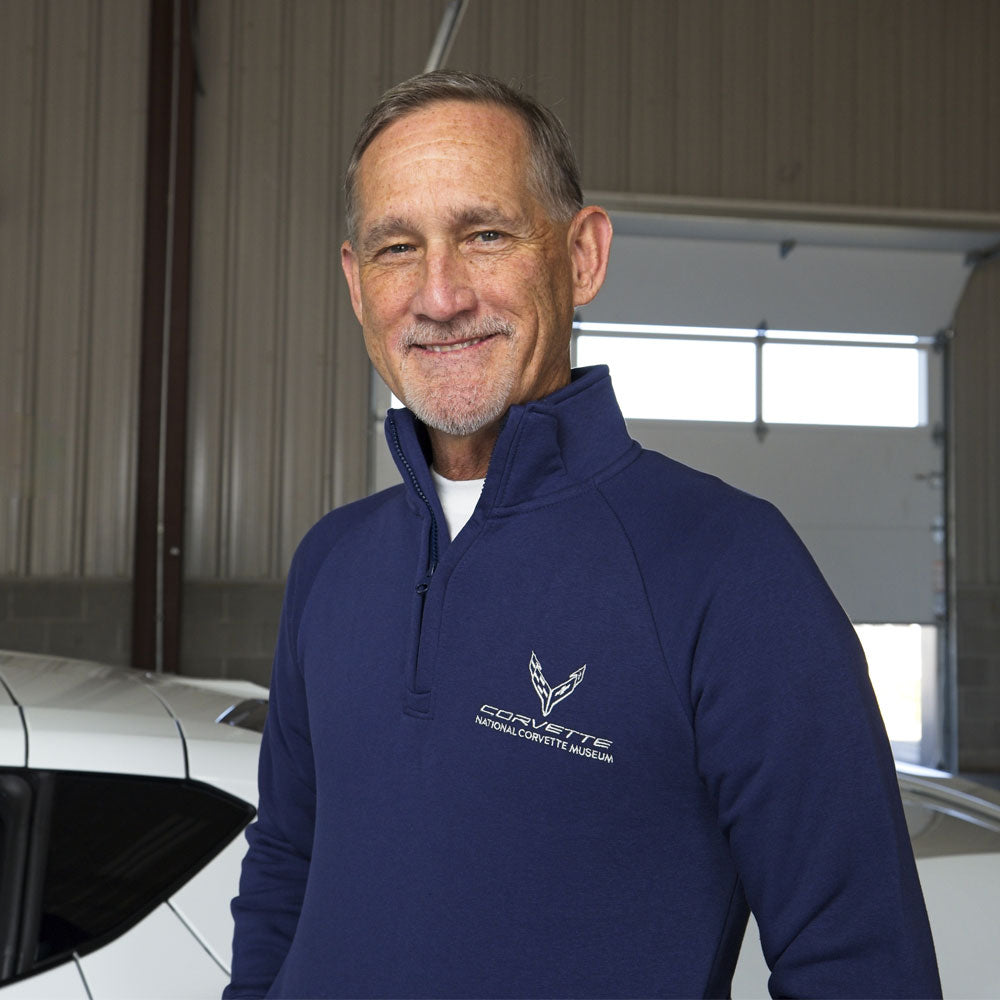 Man standing next to a white Corvette wearing the Navy C8 Corvette Emblem with Skydome Quarter-Zip.
