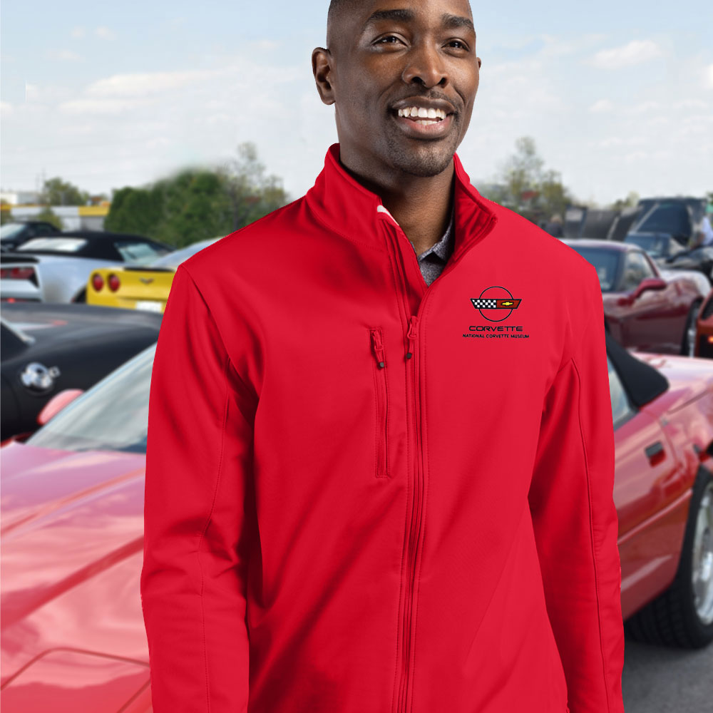 Man wearing a red jacket with the C4 Corvette emblem on the left chest standing in front of a red C4 Corvette.