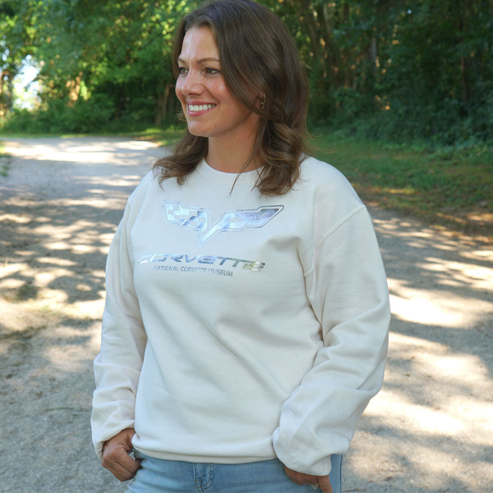 Woman walking in a park wearing the C6 Corvette Foil Emblem Classic Ivory Sweatshirt