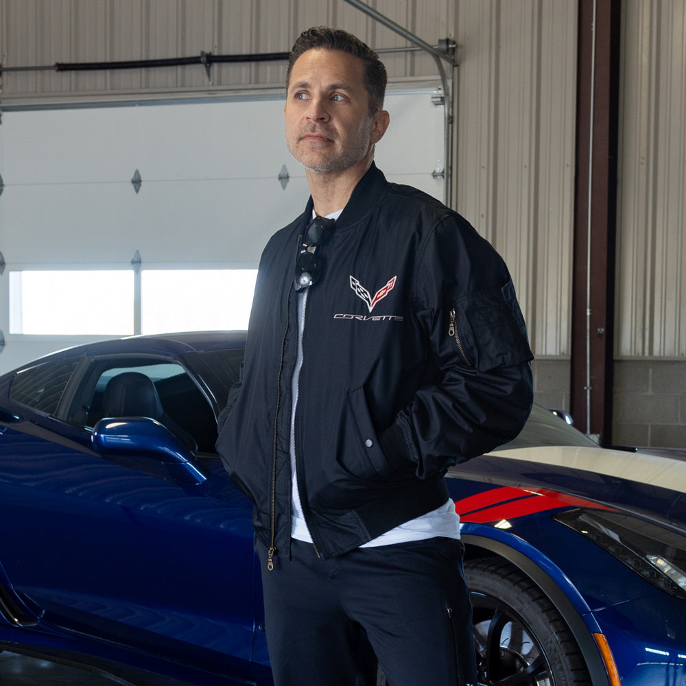 Man standing in a garage wearing the C7 Corvette Aviator Black Jacket
