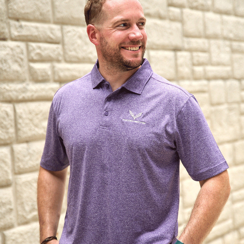 Man wearing a purple polo shirt with a C7 Corvette logo against a stone wall