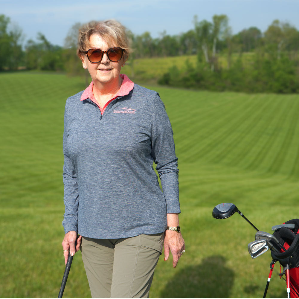 Woman wearing the C8 Corvette Gesture Ladies Mentor Heather Navy Quarter-Zip while playing golf