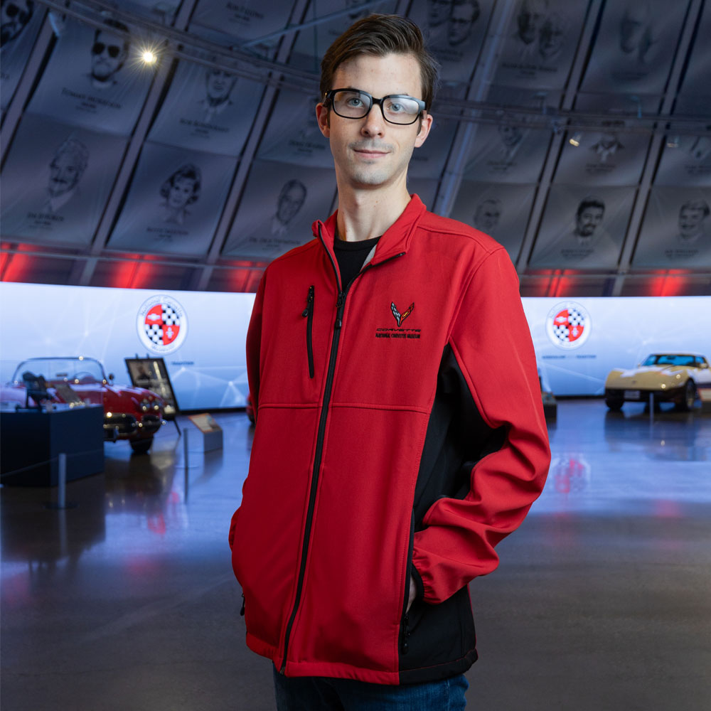 Man standing in the Corvette Museum wearing the C8 Corvette Narvik Red and Black Colorblock Jacket