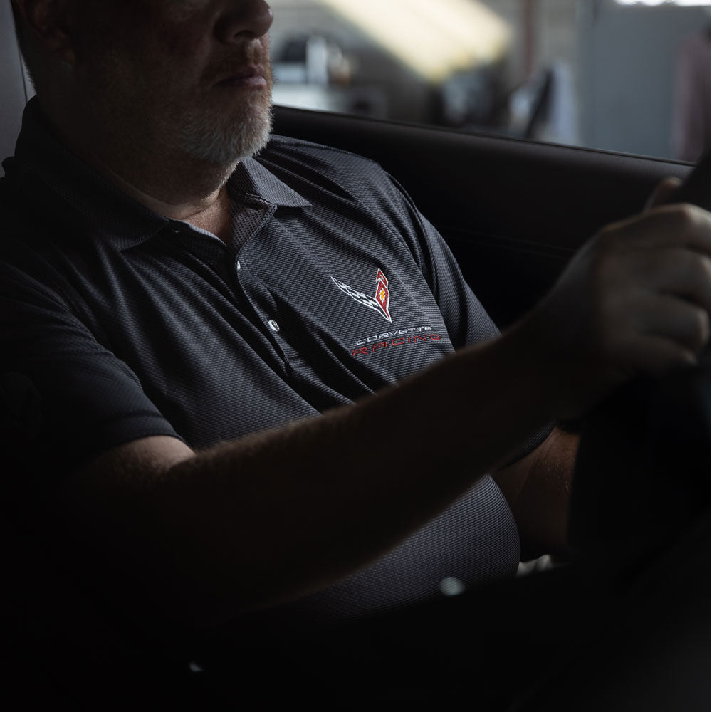 Man sitting in a Corvette wearing the C8 Corvette Racing Pebble Beach Polo