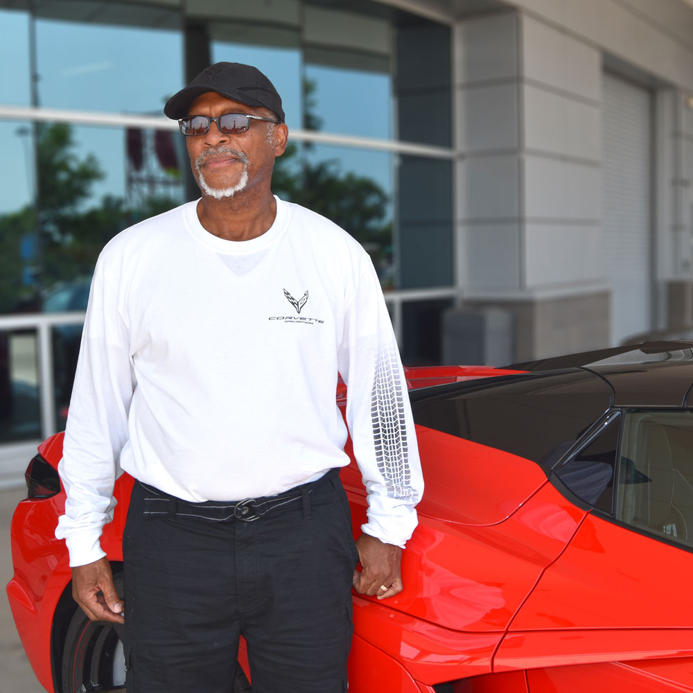 Person wearing the C8 Corvette Tire Tracks LS T-shirt in front of a Corvette