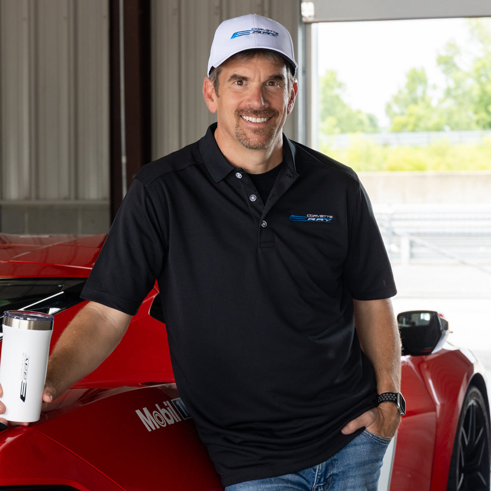 Man standing in front of a red Corvette wearing a black C8 E-Ray Corvette Emblem Callaway Polo