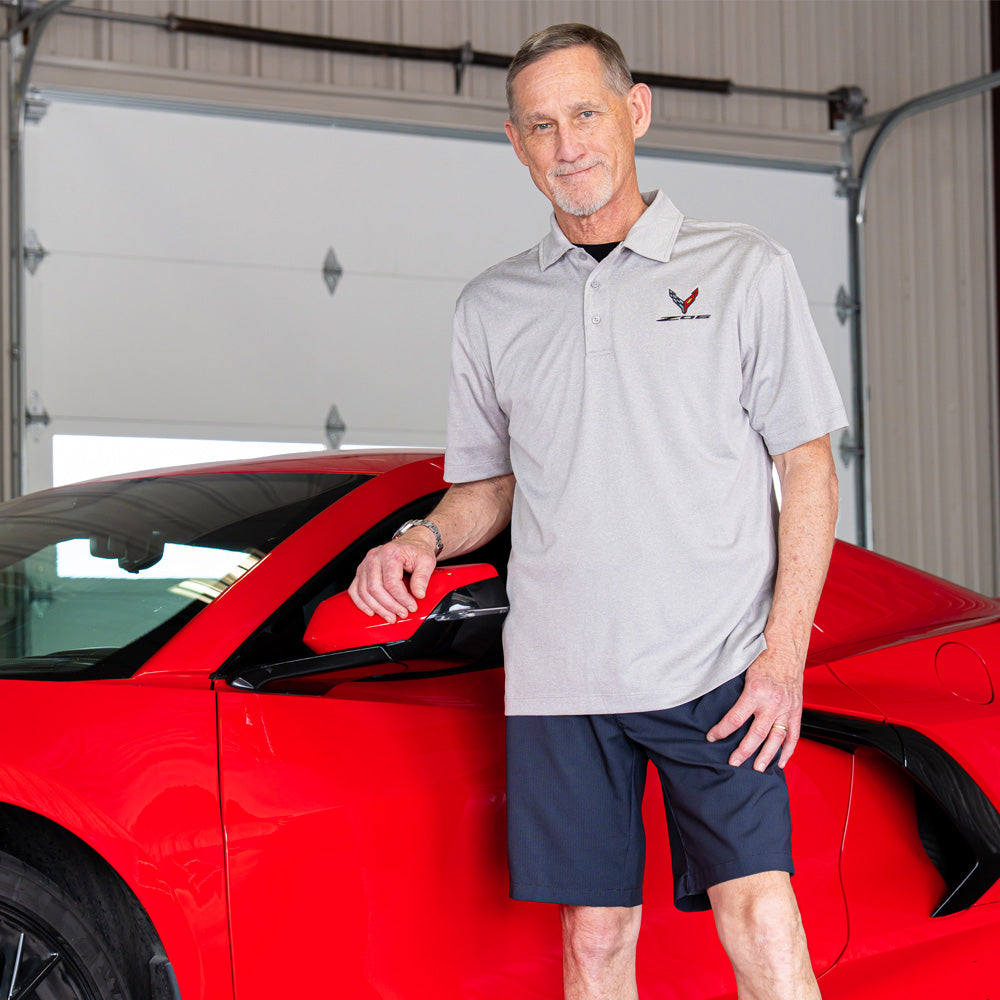 Man standing next to a red Corvette in a garage wearing the light gray C8 Z06 Corvette Polo.