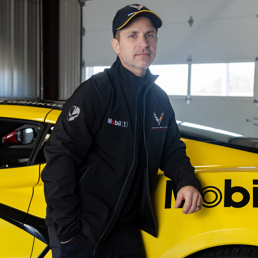 Man standing in front of a yellow Corvette wearing the C8R Corvette Racing Mobil 1 Black Jacket