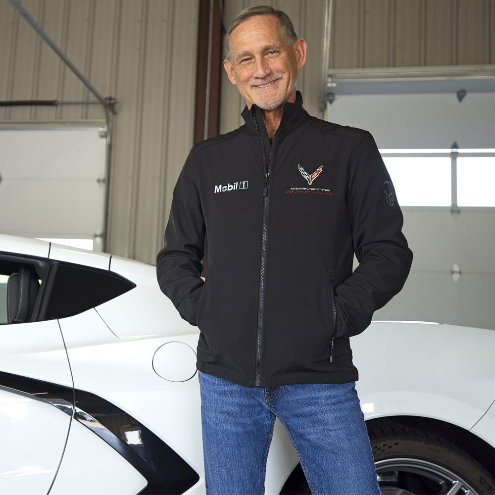Man standing in front of a white Corvette wearing the C8.R Corvette Racing Mobil 1 Black Jacket