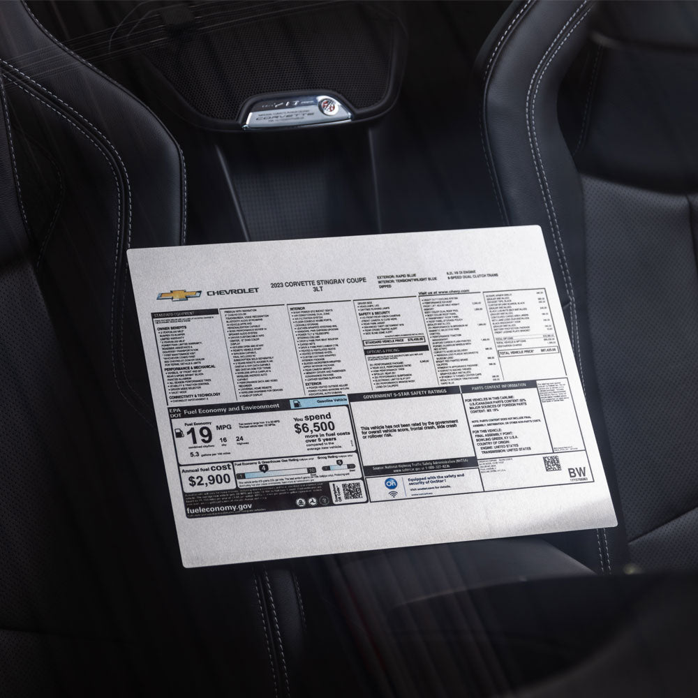 The Corvette Aluminum Window Sticker displayed on the console between the seats in a Corvette