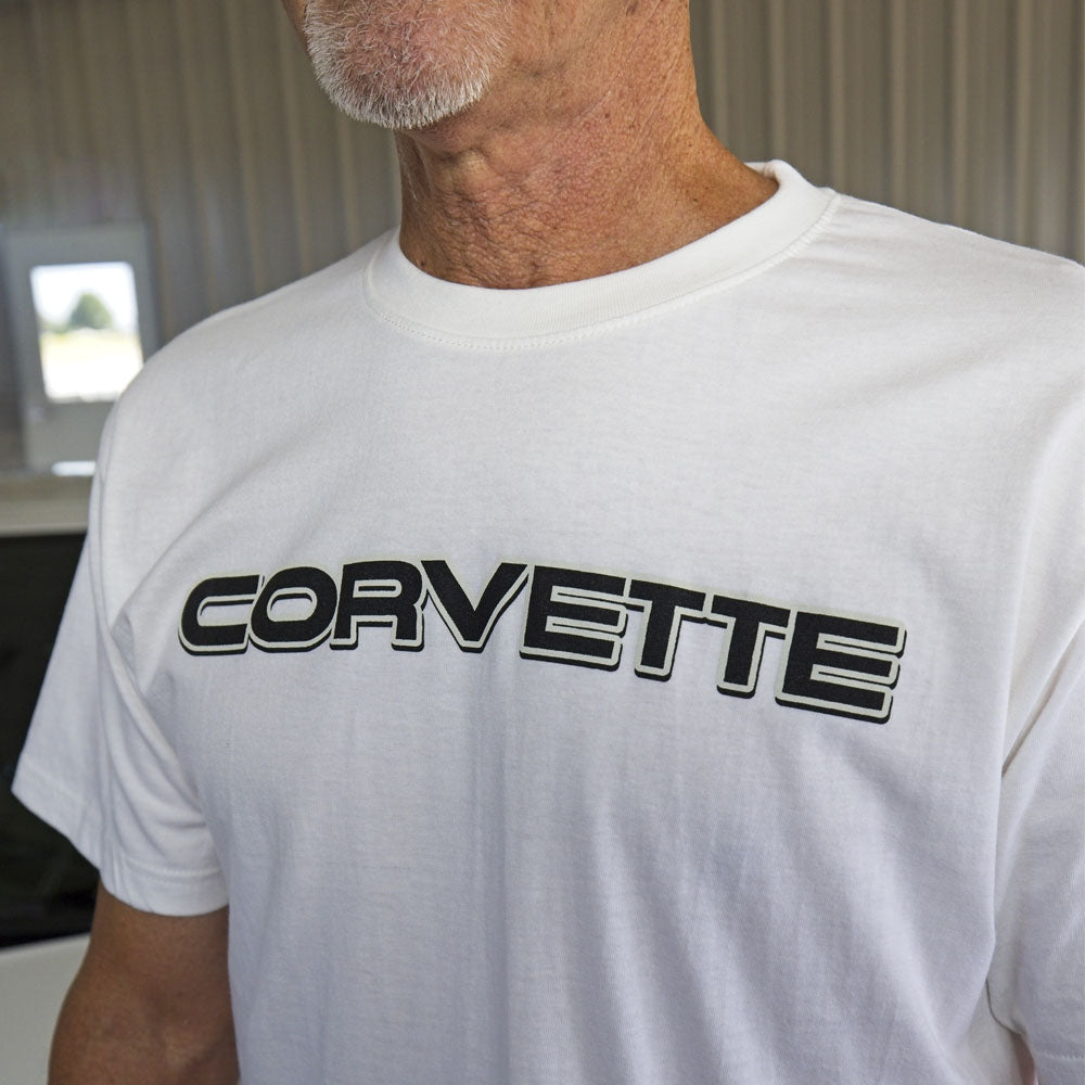 A man wearing a white t-shirt with black Corvette script on the front chest.