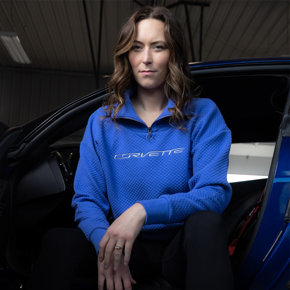Woman sitting in a blue Corvette wearing the Corvette Ladies Zip-Collar Quilted Periwinkle Pullover Lifestyle