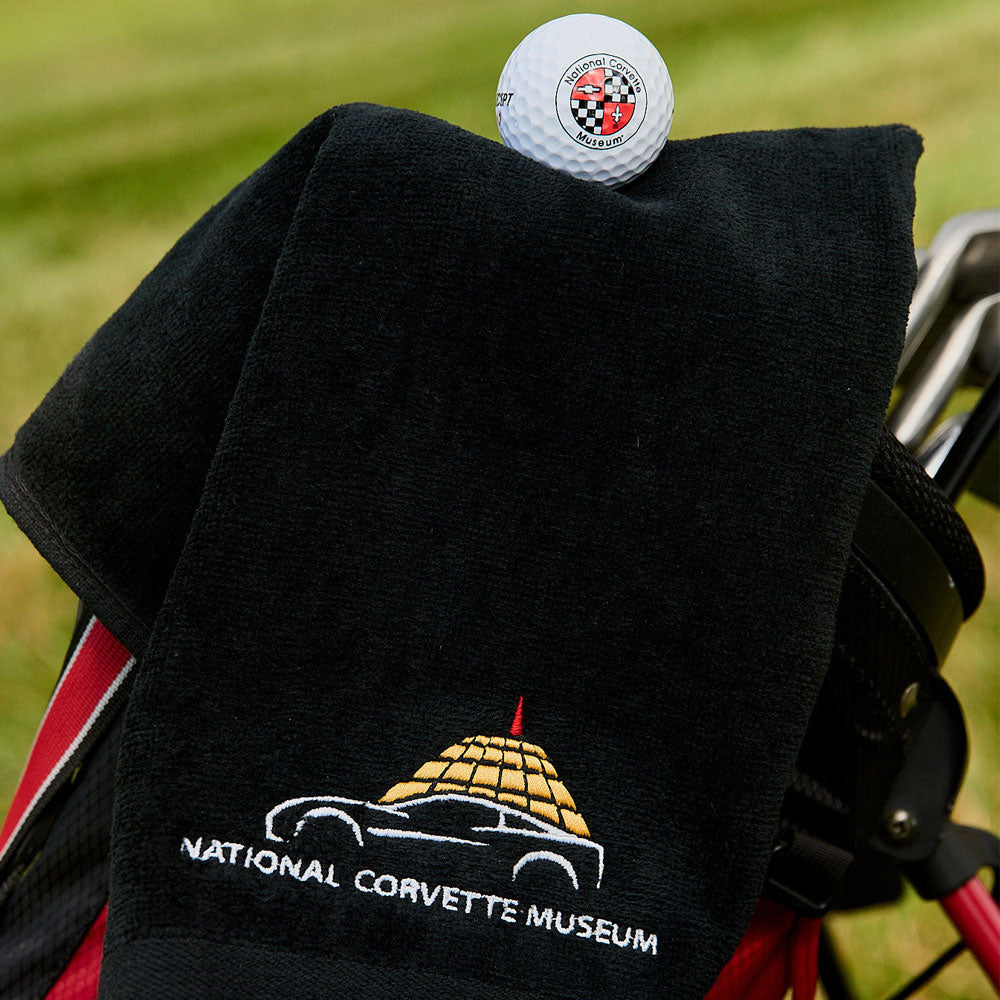 NCM Golf Towel shown with golf clubs