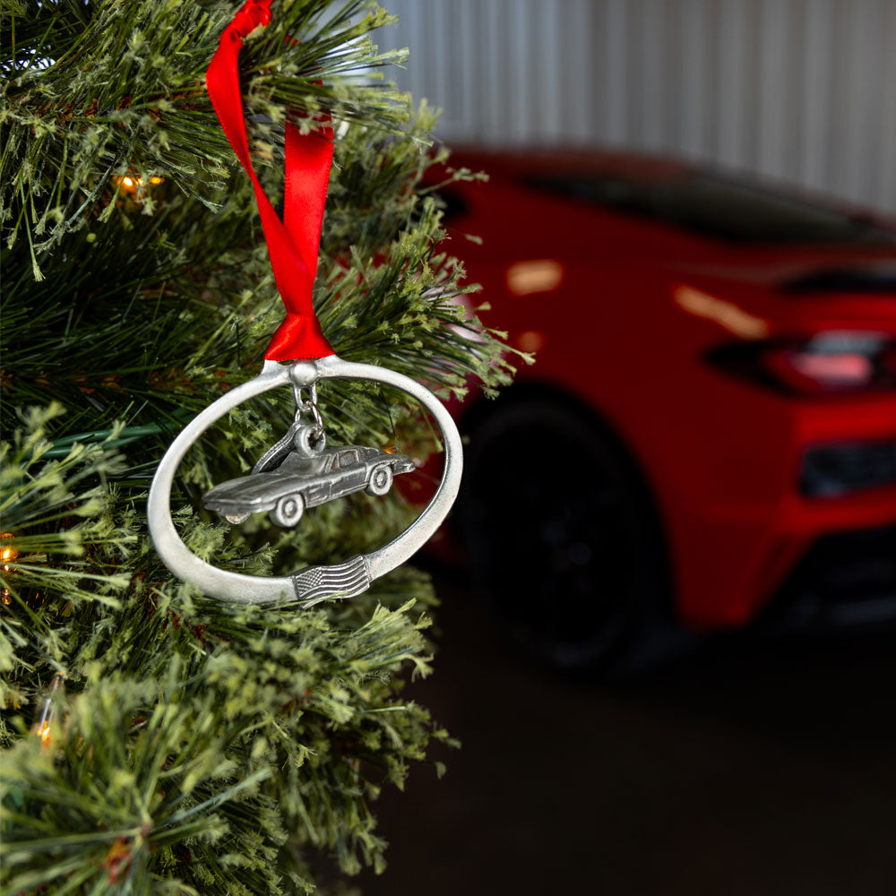 1963 Sting Ray Pewter Ornament shown hanging on a tree next to a red Corvette