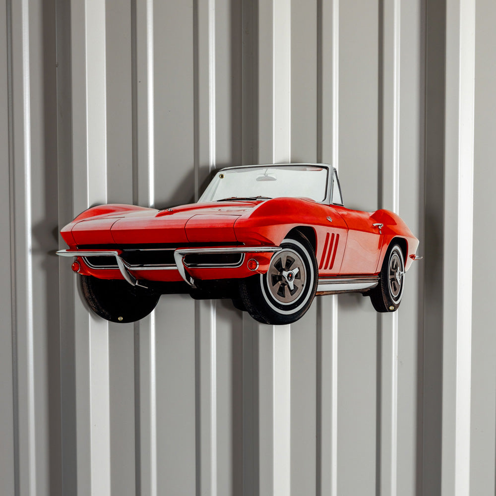 The 1965 Red Corvette Metal Sign shown hanging on the wall of a garage