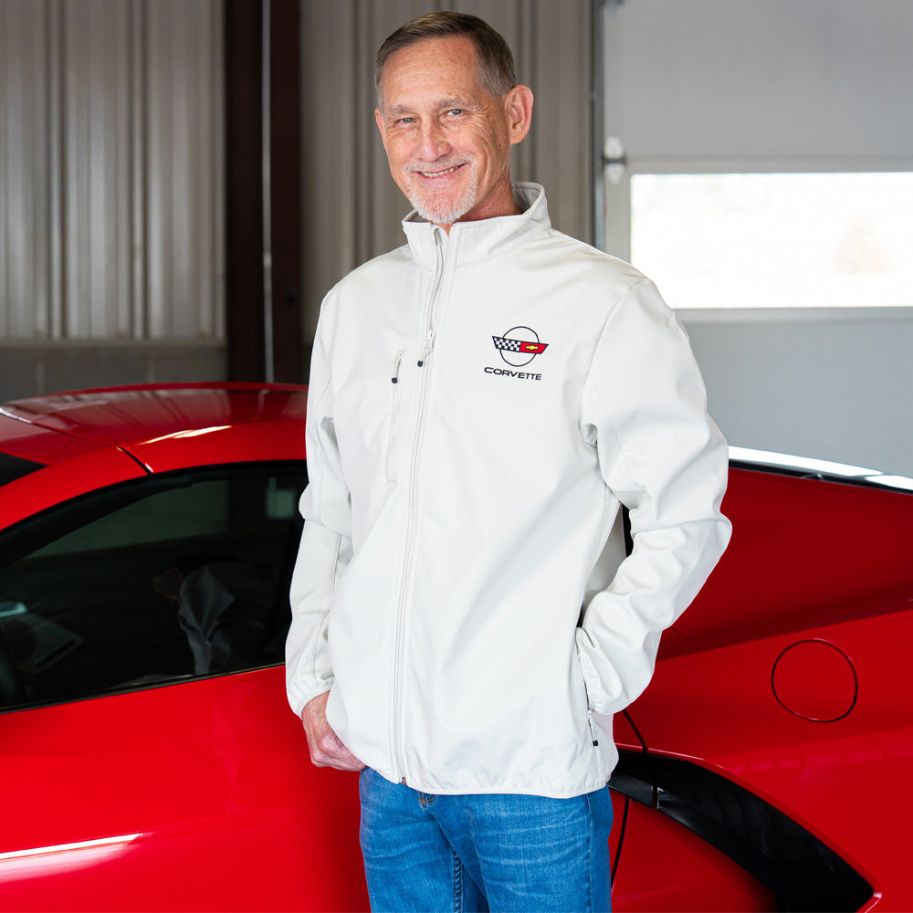 Man in an off white Corvette jacket with the C4 Corvette emblem standing next to a red Corvette.