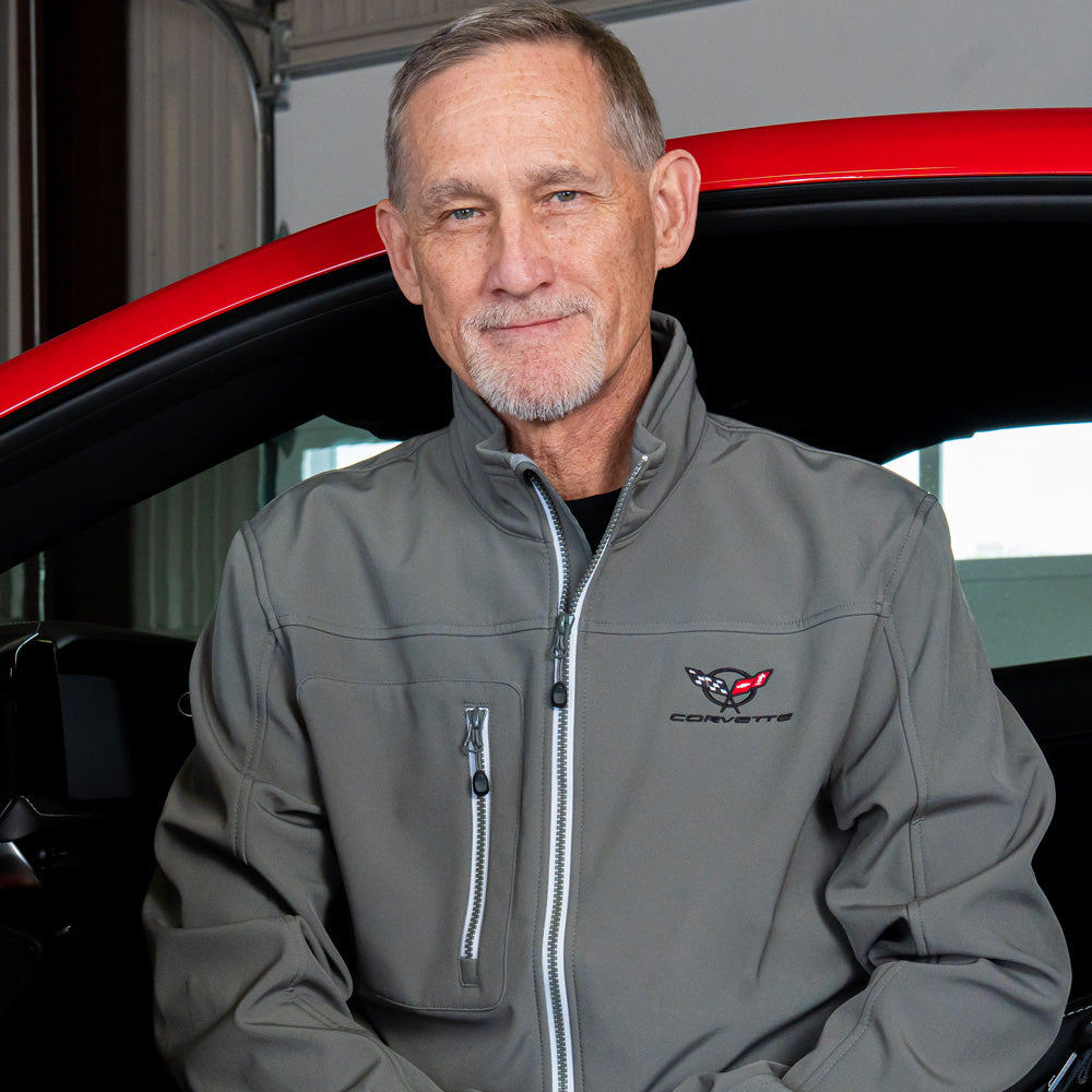 Man wearing a gray jacket with a C5 Corvette logo in front of a red Corvette.