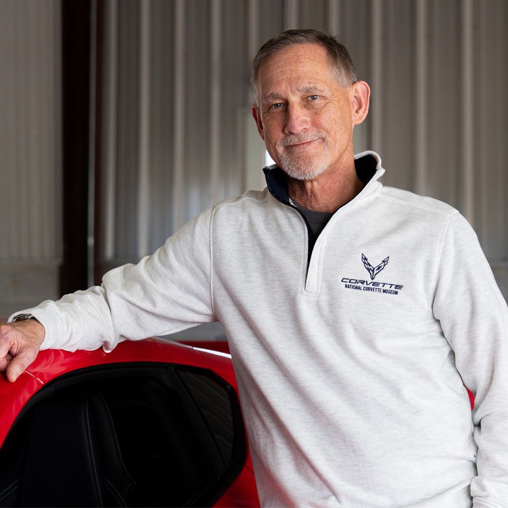 Man standing in a garage next to a Corvette wearing the Ash Gray 8th Generation Corvette Emblem Crest Quarter-Zip 