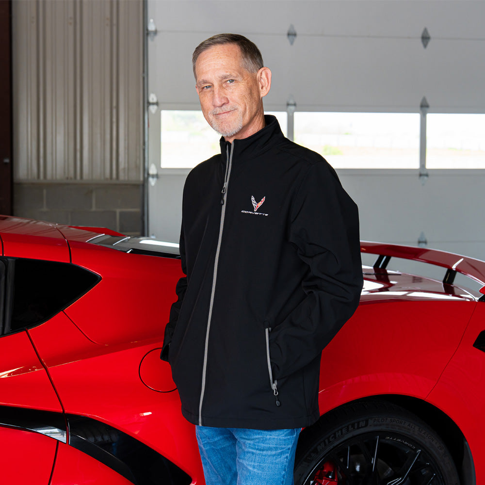 Man standing next to a red Corvette wearing the 8th Generation Corvette  Tempo Black Jacket
