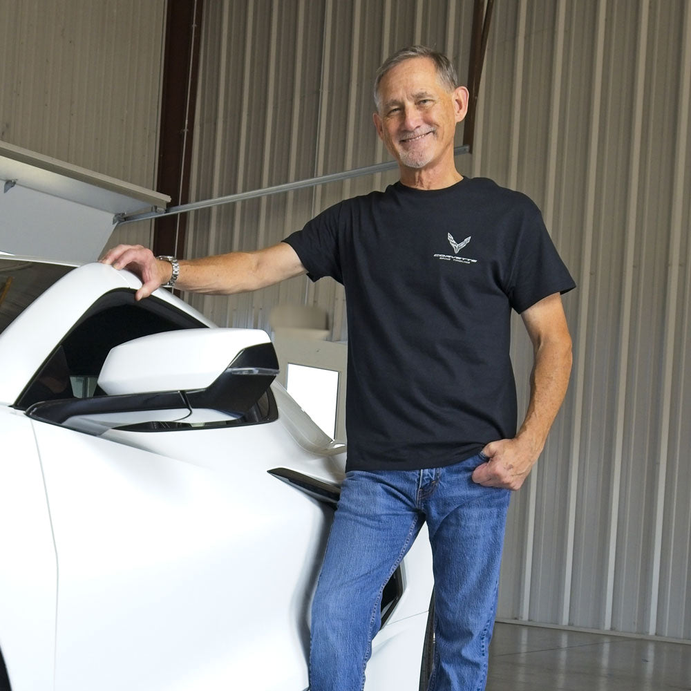 Man standing next to a white Corvette wearing the 8th Generation Corvette Spine Tingling Black T-shihrt.