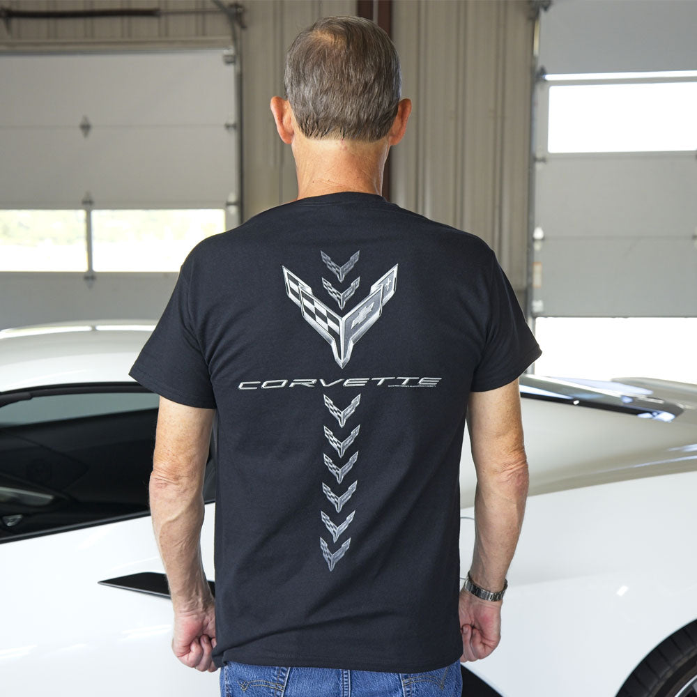 Man wearing the 8th Generation Corvette Spine Tingling T-shirt in black while standing in front of a white Corvette