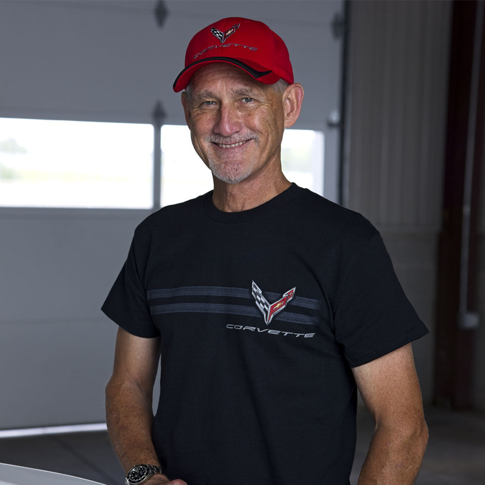 Man wearing a black Corvette tee with a C8 emblem on the front chest over a horizontal tire tracks design.