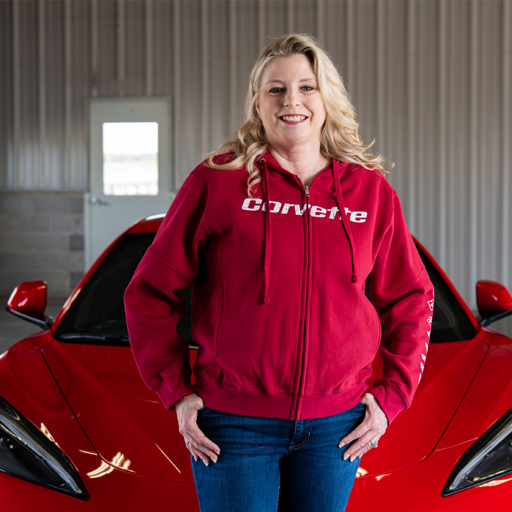 Woman standing in front of a red Corvette wearing the C1-C8 Corvette Emblems  Fleece Full Zip Red Hoodie