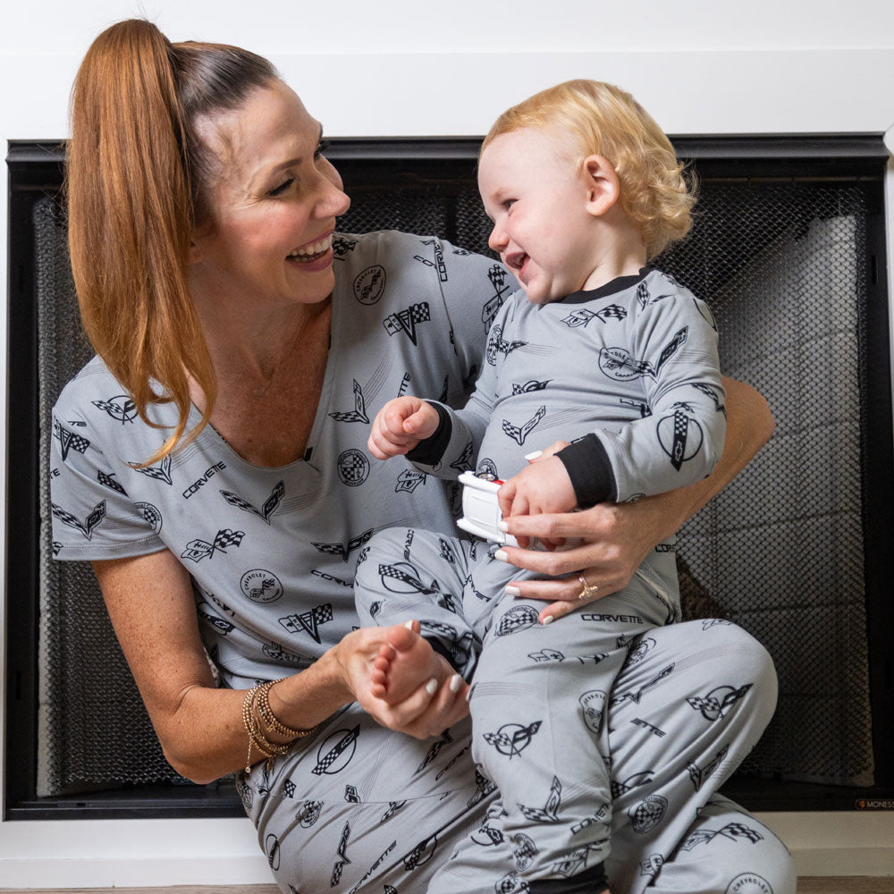 Woman wearing the C1-C8 Corvette Emblems Print Ladies Pajama Top holding a baby in matching pajamas