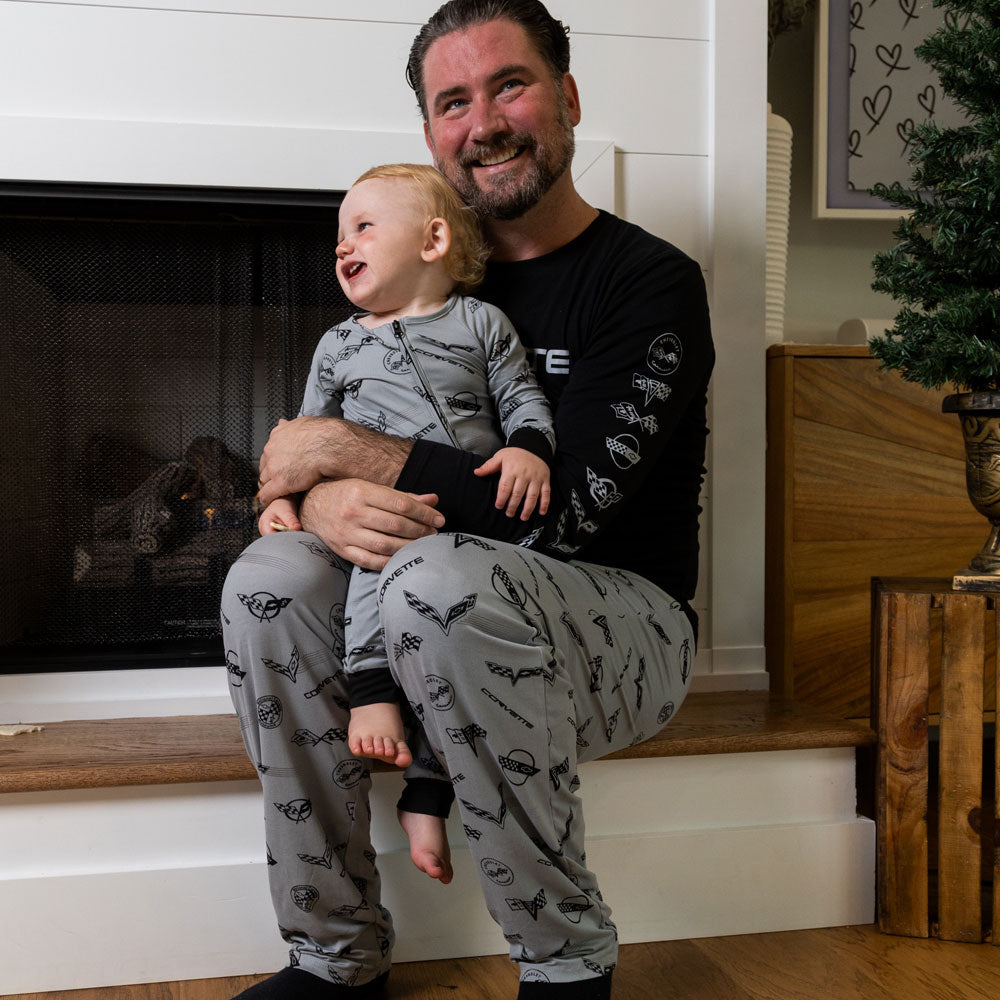 Dad wearing the C1 through C8 Corvette Emblems Print Mens Lounge Pants holding his infant son in the matching romper