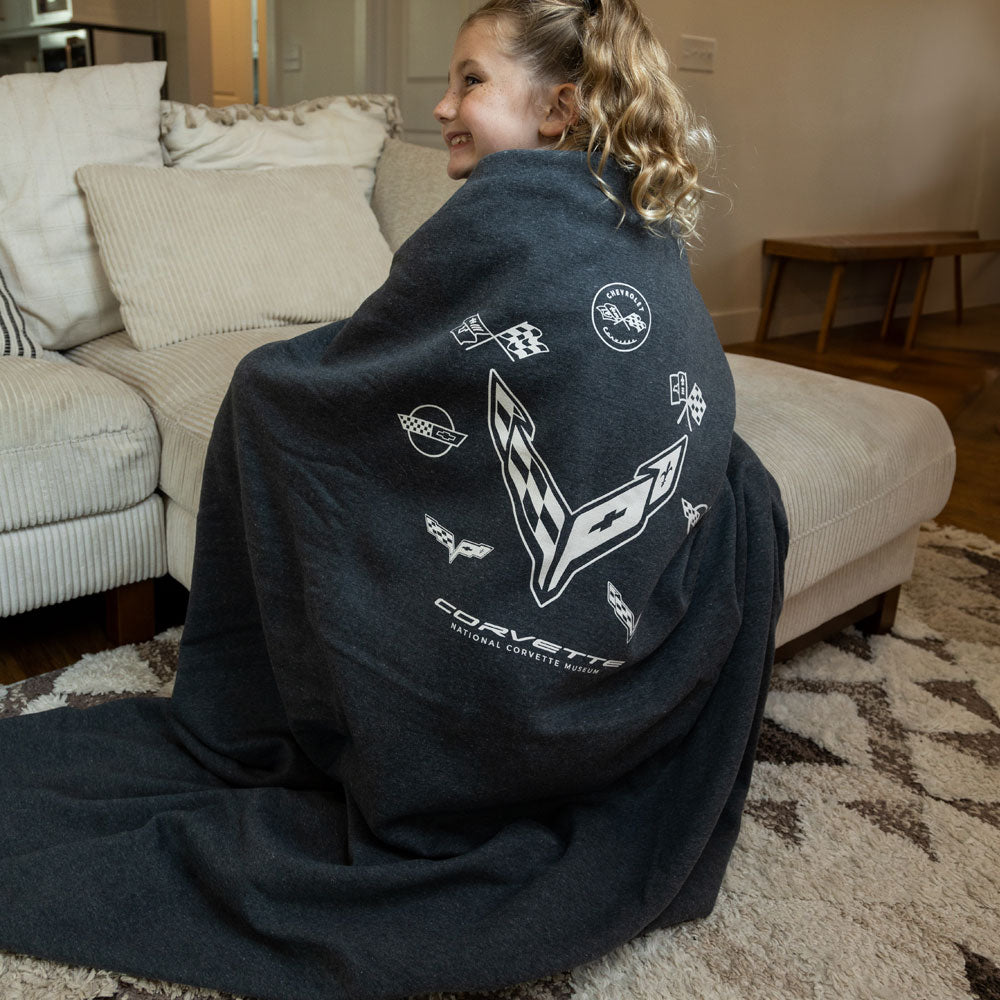 Girl sitting on the couch wrapped in the C8 Sweatshirt Blanket