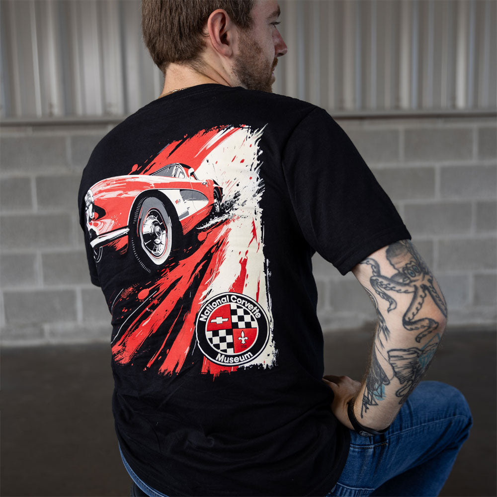 Man sitting on a stool in a garage wearing the C1 Red Corvette NCM T-shirt