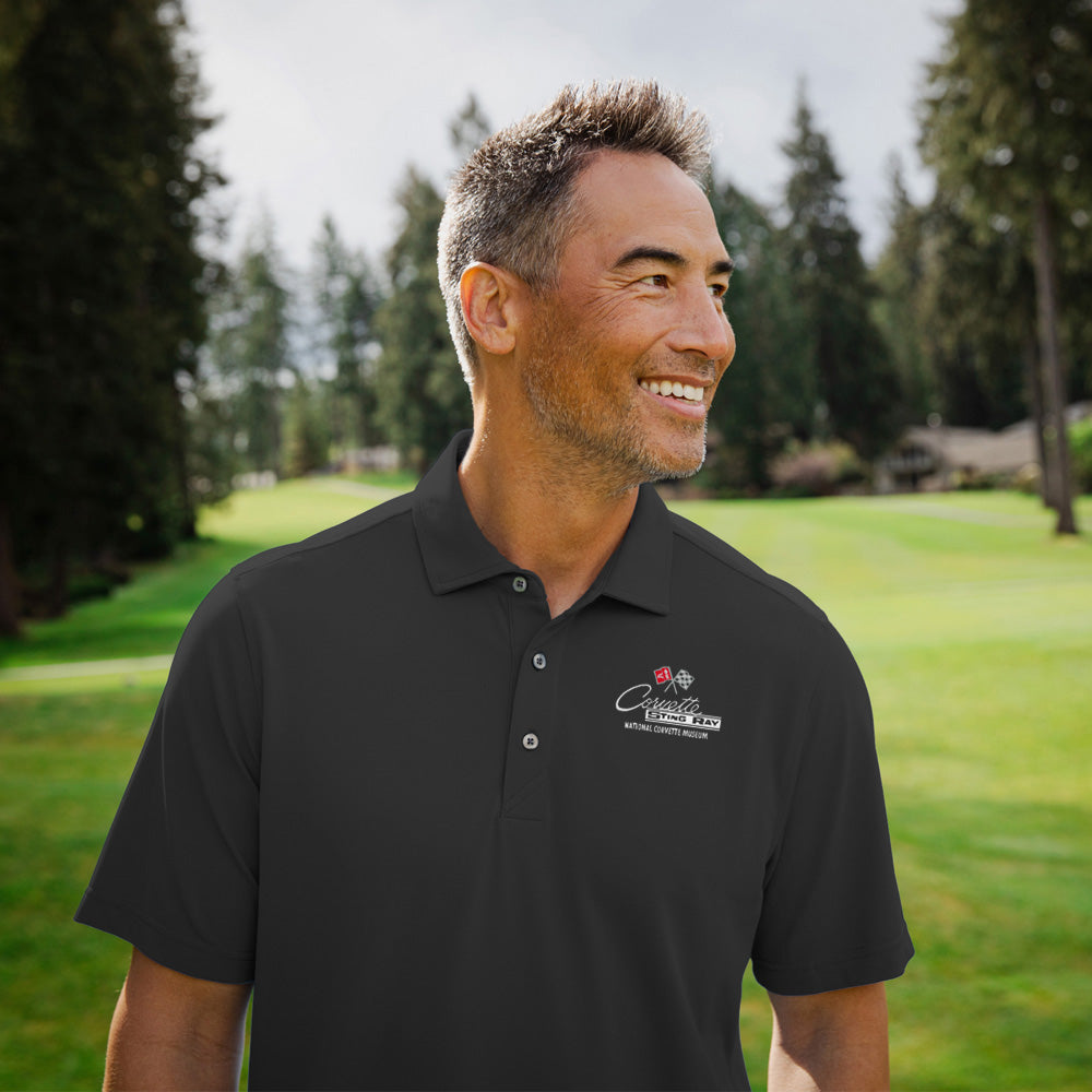 Man standing on a golf course wearing the black C2 Corvette Custom Virtue Polo