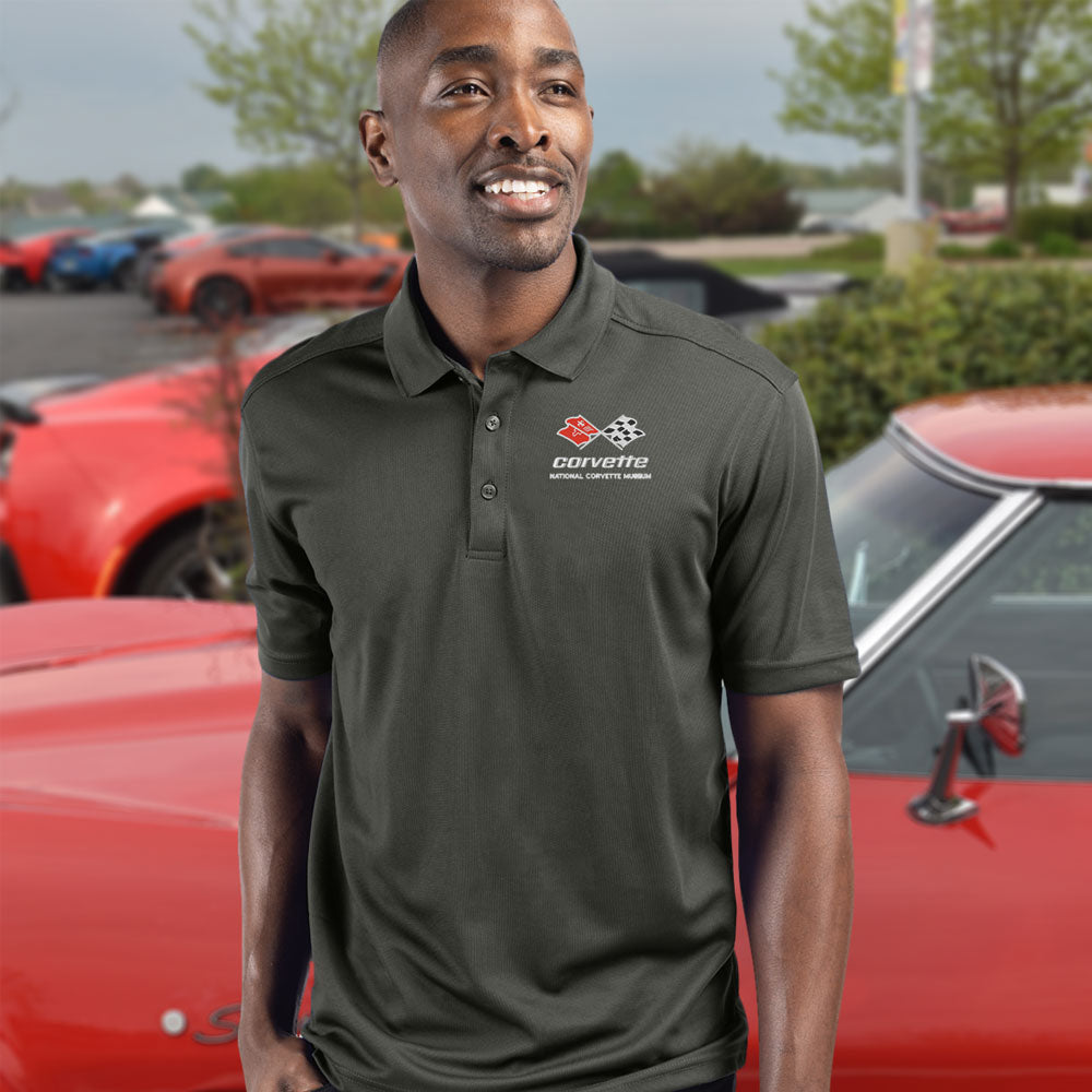 Man standing in front of a red C3 Corvette while wearing the C3 Corvette Emblem Core Spin Polo 