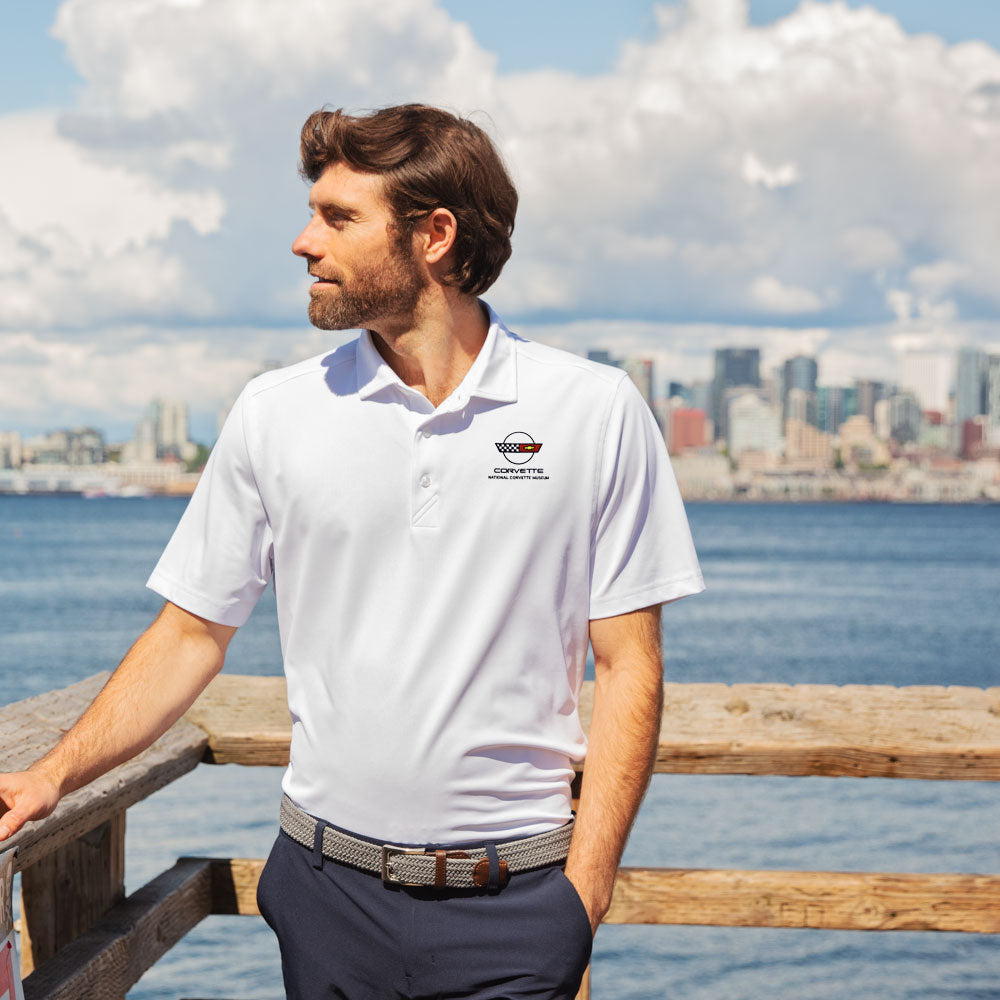 Man wearing the C4 Corvette Emblem Core White Virtue Polo while standing on a pier
