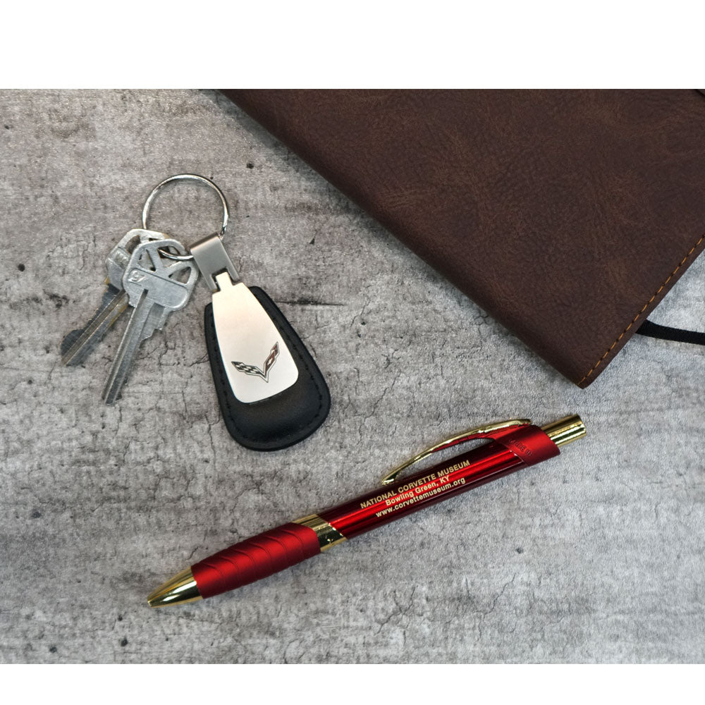 The C7 Corvette Emblem Leather Teardrop Keychain displayed on a table with a pen and notebook