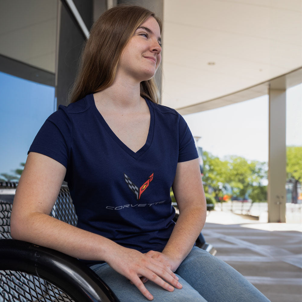 Woman sitting on a bench wearing the C8 Corvette Emblem Ladies Navy V-Neck Top 