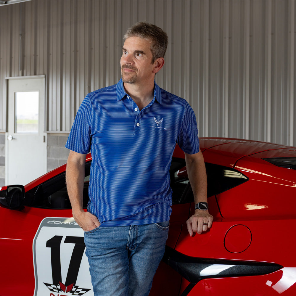 Man standing in front of a C8 Corvette wearing the Forge Fine Line Stripe Tour Blue Polo