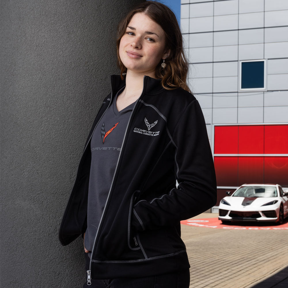 Woman wearing the C8 Corvette Ladies Black Jersey Jacket standing in front of a Corvette