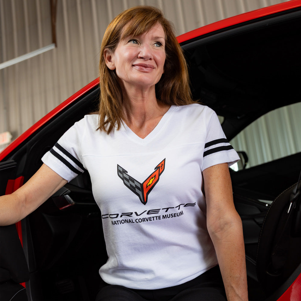 Woman wearing a Corvette football tee sitting in a red Corvette.