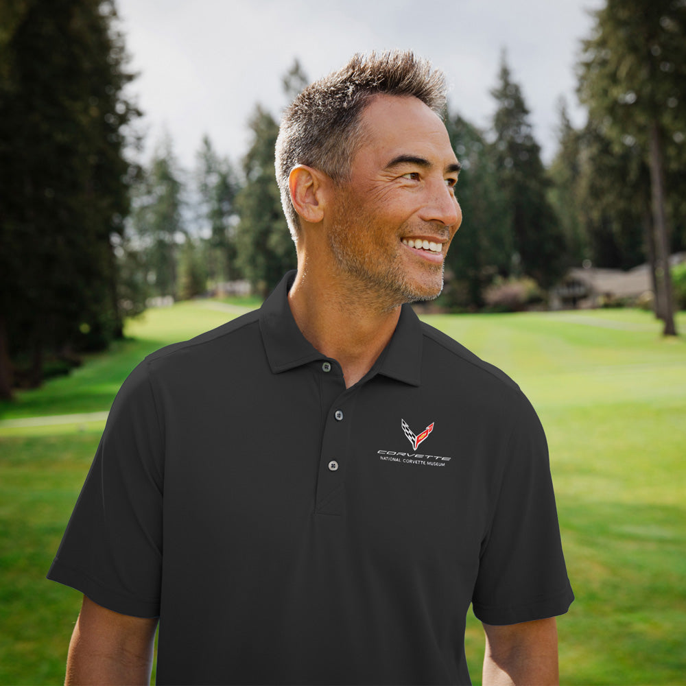 Man standing on a golf course wearing the black C8 Corvette Mens Custom Virtue Polo
