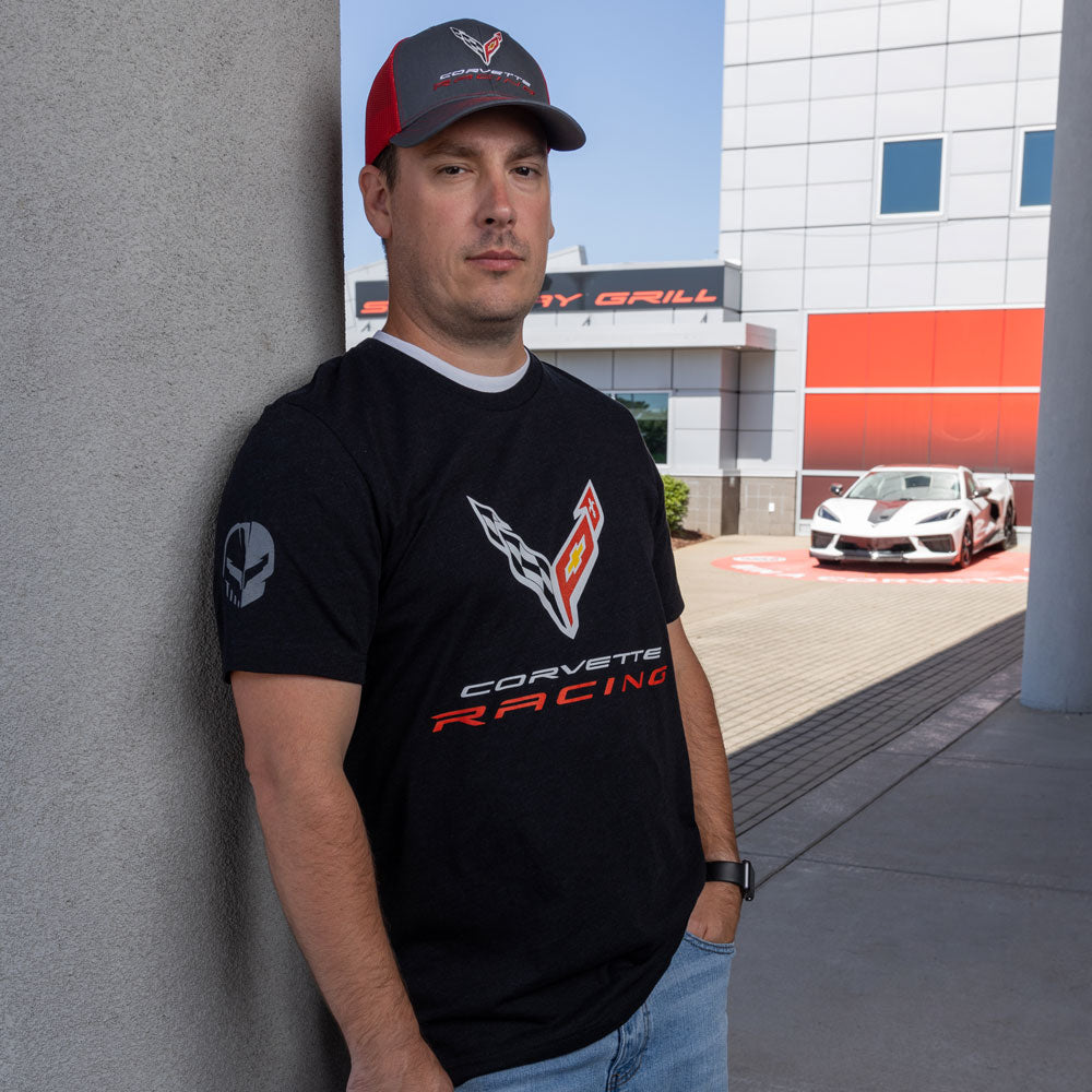 Man wearing the C8 Corvette Racing Emblem T-shirt standing in front of a White Corvette