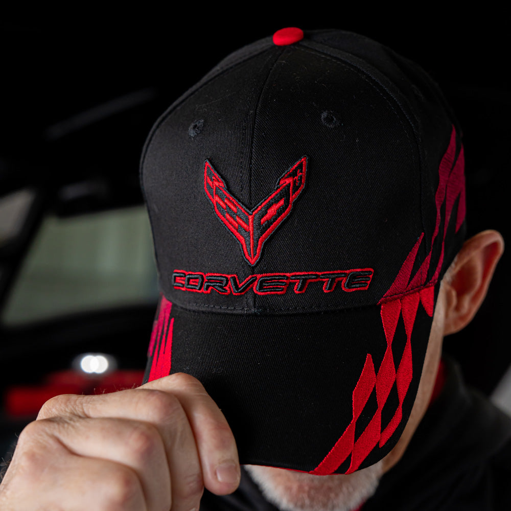 Person wearing a black and red Corvette cap with a car in the background