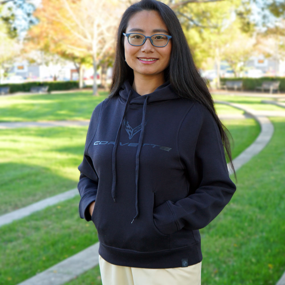 Woman standing in a park wearing a black C8 Corvette hoodie