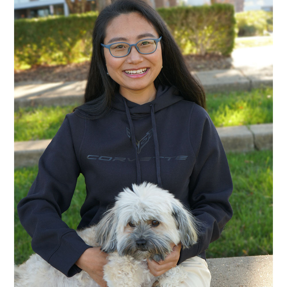 Woman holding a dog while wearing the C8 Corvette Tonal Ghost Emblem Ladies Pullover Black Hoodie 