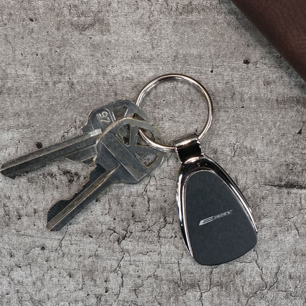 The C8 E-Ray Corvette Emblem Chrome Teardrop Keychain displayed on a table