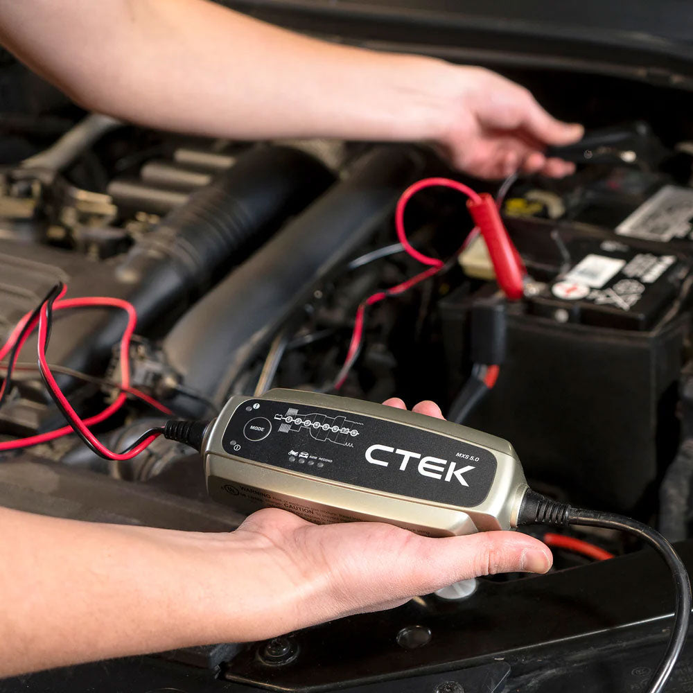 Person using the the CTEK MXS Battery Charger on a car engine