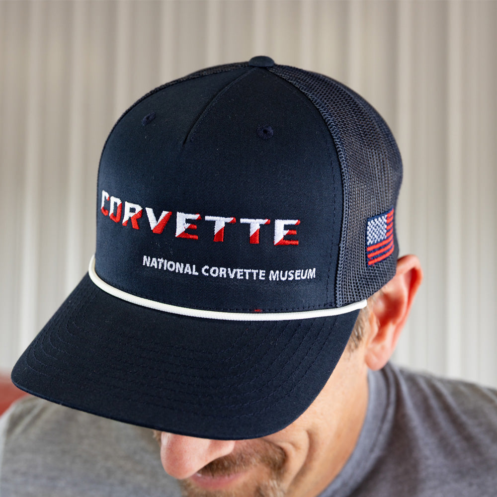 Navy blue Corvette cap with American flag logo worn by a person against a neutral background