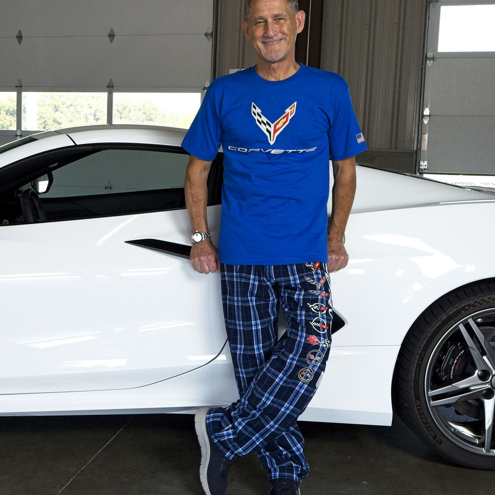 Man leaning against a white Corvette wearing the Corvette Generations Flannel Pants 