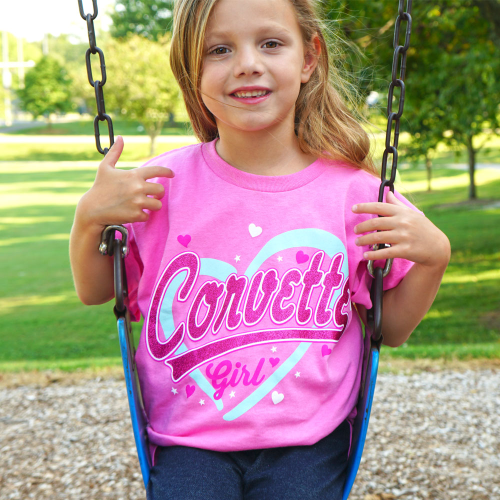 Little girl wearing Corvette Girl Pink T-shirt while swinging on a swing set